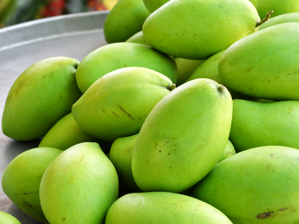 Fresh green mangoes displayed in a tray
